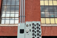 All Phase Electric LLC | Multi-meter socket bank and service conduits on a commercial brick building | Southern NH